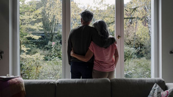 Symbolbild: Ein Seniorenpaar steht zu Hause am Fenster (Quelle: imago images/Gustafsson).