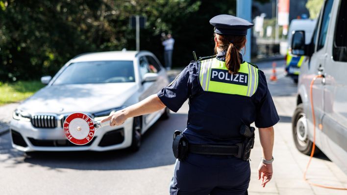 Eine Polizistin stoppt an einer Kontrollstelle an der Grenze ein Fahrzeug.