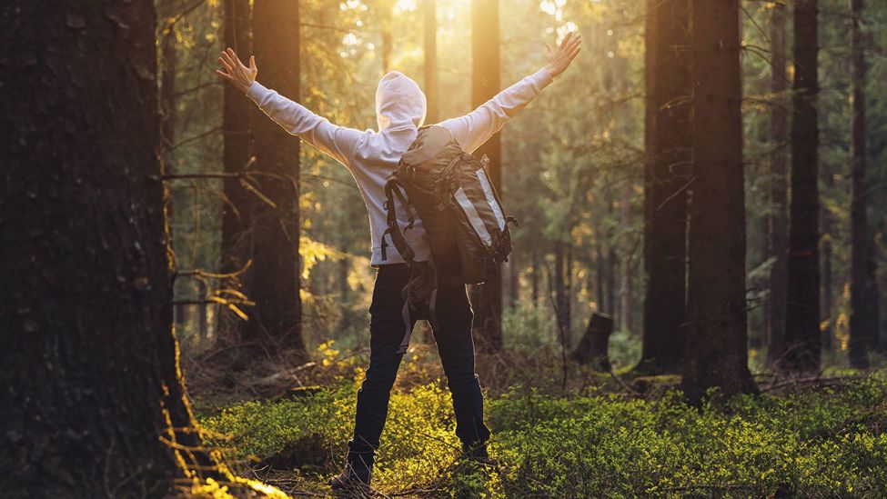 Mann freut sich beim Spaziergang im Wald (Quelle: imago/Photocase)