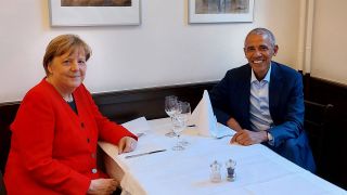 Angela Merkel, Bundeskanzlerin a. D., und Barack Obama, früherer US-Präsident, sitzen gemeinsam beim Essen in einem Restaurant. (Quelle: dpa/Bildfunk)