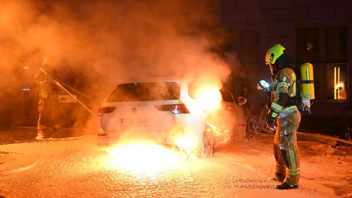 Einsatzkräfte der Feuerwehr löschen ein angezündetes Auto in der Nacht zum 27.07.2023 auf einem Parkplatz in Berlin-Mitte vor einem Gebäude der Deutschen Bahn.(Quelle:Morris Pudwell)