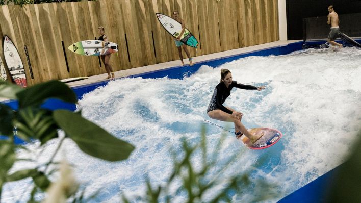 Archivbild: Eine Surferin springt auf einer künstlichen Surfwelle in der Indoor-Surfhalle Wellenwerk. (Quelle: dpa/C. Koall)