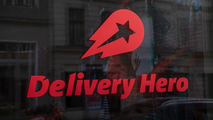 Das Logo und der Schriftzug des Essenslieferdienstes Delivery Hero ist am 11.02.2022 in einer Scheibe am Firmensitz des Unternehmens zu sehen. (Quelle: dpa-Zentralbild/Paul Zinken)