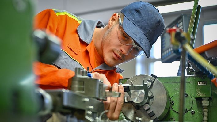 Symbolbild: Jonas Kraske, Auszubildender im Stahlwerk von ArcelorMittal, arbeitet am 08.03.2023 im Berufsbildungszentrum an einer Drehbank. (Quelle: Picture Alliance/Patrick Pleul)