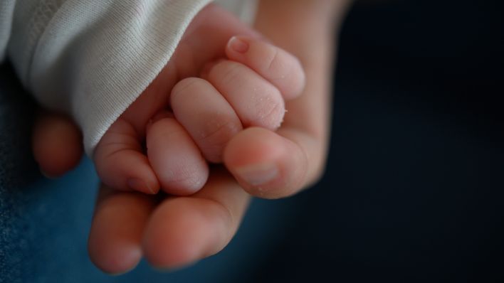 Symbolbild: Die Hand eines zwei Wochen alten Neugeborenen liegt in der Hand seiner Mutter. (Quelle: dpa-Bildfunk/Sebastian Gollnow)