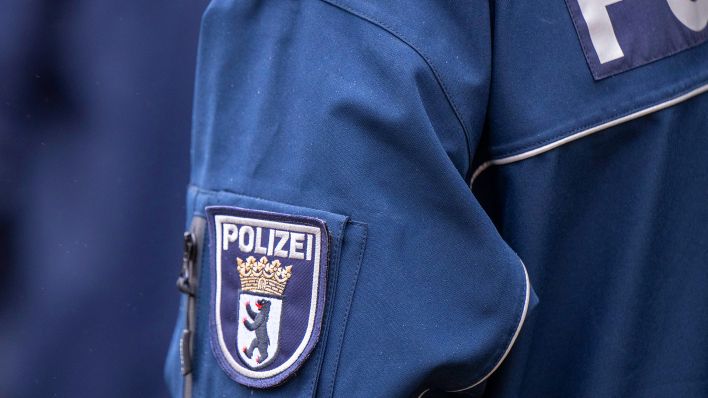 Symbolbild: Die Aufschrift Polizei und das Wappen von Berlin auf der Uniform eines Polizeibeamten. (Quelle: dpa/Monika Skolimowska)