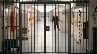Symbolbild: Ein Vollzugsbeamter öffnet am 07.12.2023 in der Justizvollzugsanstalt Moabit bei der Vorstellung der Pläne für einen Suizidpräventionsraum eine Zellentür in einem mit Gittern gesicherten Zellengang (Quelle: dpa / Jens Kalaene).