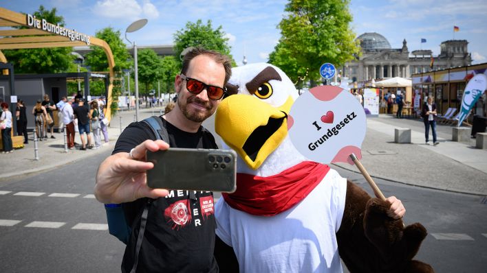 Ein Besucher macht am 24.05.2024 ein Selfie-Foto mit «Freddi dem Familienadler». (Quelle: dpa/Bernd von Jutrczenka)