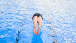 Ein Badegast springt im Freibad Annabad in Brandenburg mit einem Kopfsprung ins Wasser.