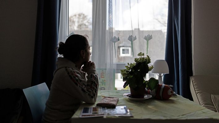 Symbolbild:Eine Frau sitzt im Frauenhaus am Fenster und schaut hinaus.(Quelle:imago images/Funke Foto Services)