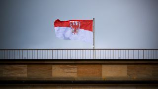 Symbolbild: Die Flagge des Landes Brandenburg mit dem roten Adler weht auf dem Landtag vor grauem Himmel. (Quelle: dpa/Soeren Stache)