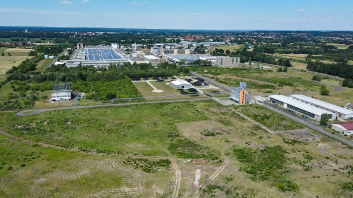 Auf dieser noch leeren Fläche am Rande eines Industriegebietes ist die Ansiedlung eines Werkes des kanadischen Rohstoff-Unternehmens Rock Tech Lithium geplant (Luftaufnahme mit einer Drohne). (Quelle: dpa/Patrick Pleul)