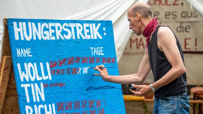 Klimaaktivist Wolfgang Metzeler-Kick, 49, befindet sich im Hungerstreik und in Lebensgefahr. Hier markiert er auf einer Tafel mit einem Pinselstrich den 85. Tag der Aktion, andere Mitstreiter hatten ihren Hungerstreik schon vorher abgebrochen. (Quelle: dpa/Wolfgang Maria Weber)