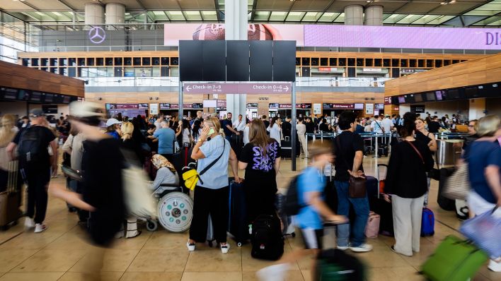 Zahlreiche Passagiere warten vor einer schwarzen Anzeigetafel am Hauptstadtflughafen BER. Am Flughafen BER ist der Flugverkehr eingestellt. Als Grund werden technische Probleme genannt. (Quelle: dpa/Soeder)