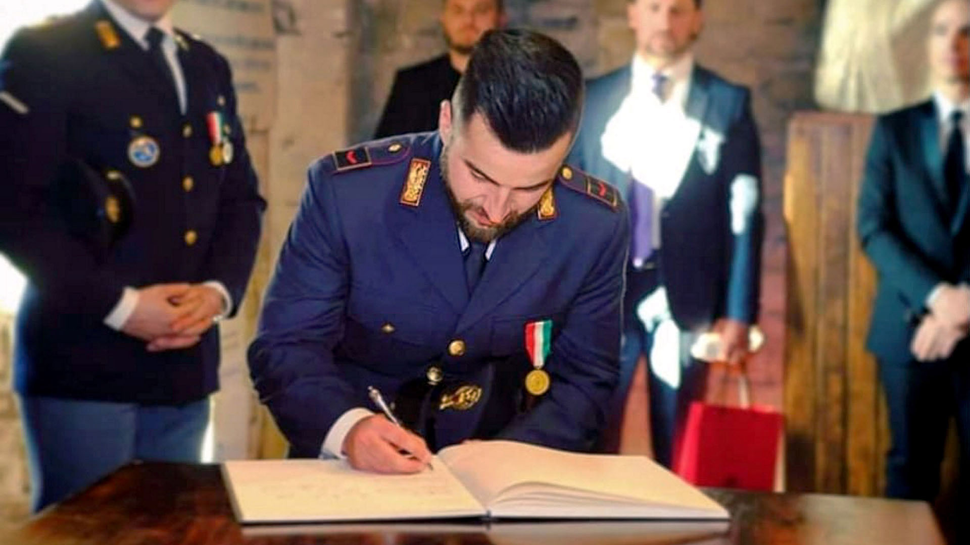 Archivbild: Polizsit Luca Scata trägt sich in ein Ehrenbuch ein. (Quelle: dpa/Ropi)