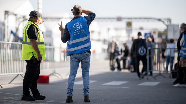 Symbolbild: Helfer und Sicherheitskräfte stehen in der Notunterkunft für Geflüchtete am ehemaligen Flughafen Tegel. (Quelle: dpa/Gollnow)