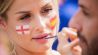 Patricia malt bei einem Fantreffen spanischer Fans an der Messe einem Fan die spanische Flagge auf die Wange (Quelle: dpa/Christoph Soeder)