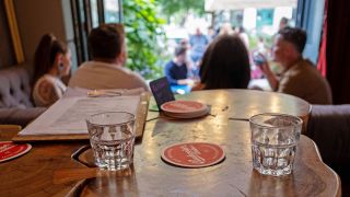 Symbolbild: Zwei Wassergläser stehen auf einem Tisch in einer gut besuchten Berliner Bar.(Quelle:imago images/snapshot-photography/T.See)