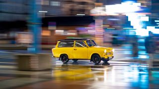 Ein gelber Trabant Kombi ist am Abend bei Regen in der Altstadt unterwegs (Quelle: dpa-Zentralbild/Jens Büttner).