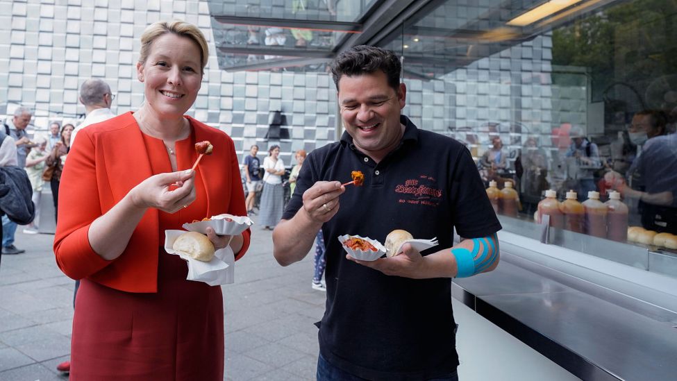 Franziska Giffey isst eine Currywurst an einem Stand (Quelle: dpa/Flashpic/Jens Krick).