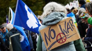 Archivbild:Eine Teilnehmerin der Friedensdemonstartion am 03.10.2024 trägt ein Schild mit der Aufschrift "No War" auf dem Rücken.(Quelle:picture alliance/dpa/J.Carstensen)