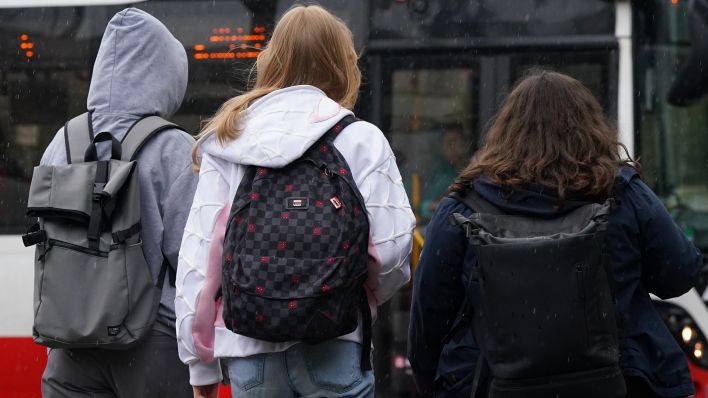 Symbolbild: Zwei Schülerinnen und ein Schüler warten auf einen Bus. (Quelle: dpa/Marcus Brandt)