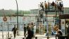 Archivbild:Aussichtsplattform mit Besuchern am Potsdamer Platz in West-Berlin. Links stehen Grenzbeamte hinter Absperrgittern. Aufnahme vom 1988.(Quelle:picture alliance/dpa/C.Hoffmann)