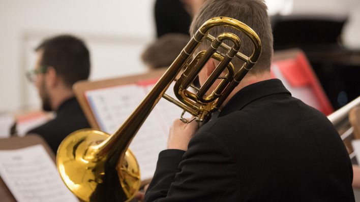 Ein Musiker spielt während einer Probe auf einer Bassposaune. (Quelle: dpa/Sebastian Kahnert)