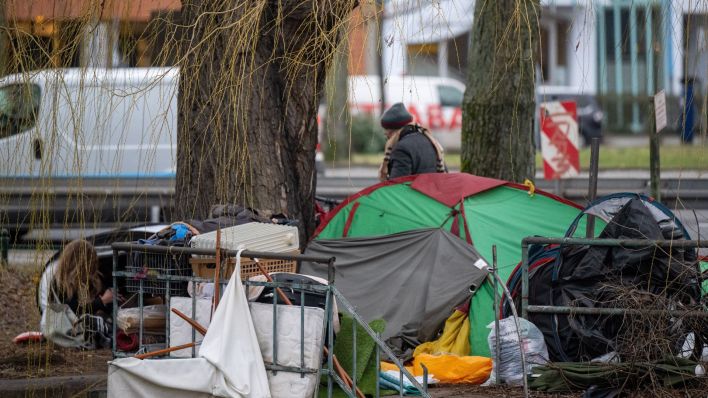 Eine wohnungslose Person sitzt an einem Zelt im Obdachlosenlager am Lützowufer. (Quelle: dpa/Monika Skolimowska)