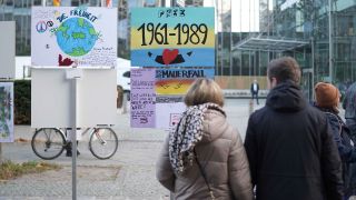 Spaziergänger sehen sich am 09.11.2024 Plakate zum 35. Jubiläum des Mauerfalls entlang des Verlaufs der früheren Mauer in der Zimmerstraße an (Quelle: rbb / Schneider).