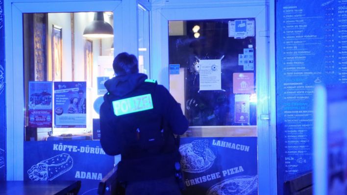 Ein Polizist untersucht Einschüsse in einer Dönerfiliale in Berlin Spandau