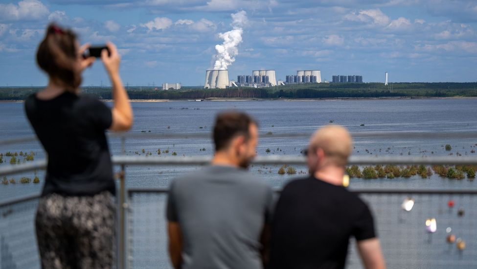 Besucher genießen bei sonnigem Wetter den Blick auf die Cottbuser Ostsee und das LEAG-Kraftwerk Jänschwalde vom Aussichtsturm Merzdorf. (Quelle: dpa/Monika Skolimowska)