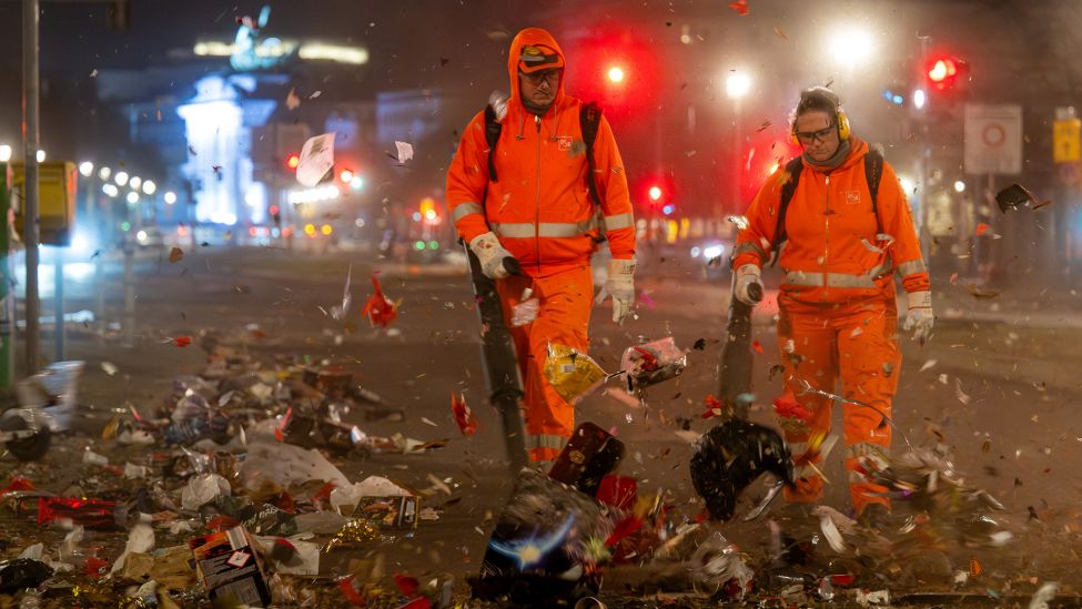 Mitarbeiter der Berliner Stadtreinigung (BSR) blasen am 01.01.2025 mit Laubbläsern den Müll der Silvesternacht auf die Ebertstraße, wo sie später von einer Kehrmaschine beseitigt wird. (Quelle: dpa-Bildfunk/Soeren Stache)