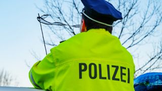 08.01.2025, Brandenburg, Frankfurt (Oder): Ein Polizeibeamter steht vor dem Trauerflor an einer Antenne seines Einsatzfahrzeuges am Polizeipräsidium Ost.(Quelle:dpa/P.Pleul)