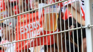 Bier-Becher hängt am Zaun neben einer Fahne von Union Berlin (Quelle: IMAGO / Nordphoto)